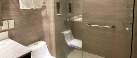 A modern bathroom with a glass-enclosed shower, a toilet, and a vanity with a towel rack.