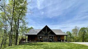 Un chalet rustique avec une façade en pierre, un toit en pente et une véranda dotée de sièges pour l’extérieur.