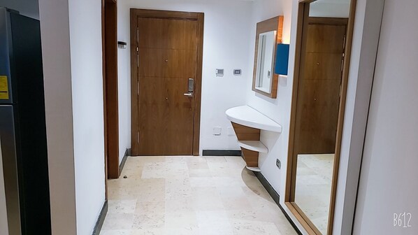 A narrow hallway with a wooden door, a white sink, and a mirror.