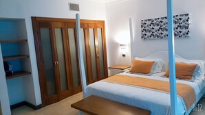 A hotel room with a bed, a nightstand, a wardrobe, and a shelf unit. - Playa Resort hamaca  (Boca Chica)