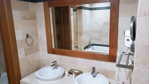 A bathroom with two sinks, a mirror, and a hairdryer mounted on the wall.