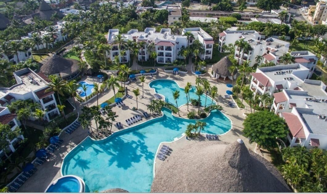 A resort with multiple swimming pools, palm trees, and resort buildings.