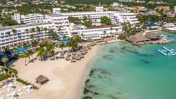 A beachfront hotel with multiple balconies, a pool area, and a beach with umbrellas. - Playa Resort hamaca  (Boca Chica)