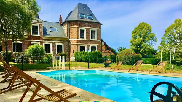 Une piscine avec des chaises longues et un grand flotteur gonflable en forme de beignet.