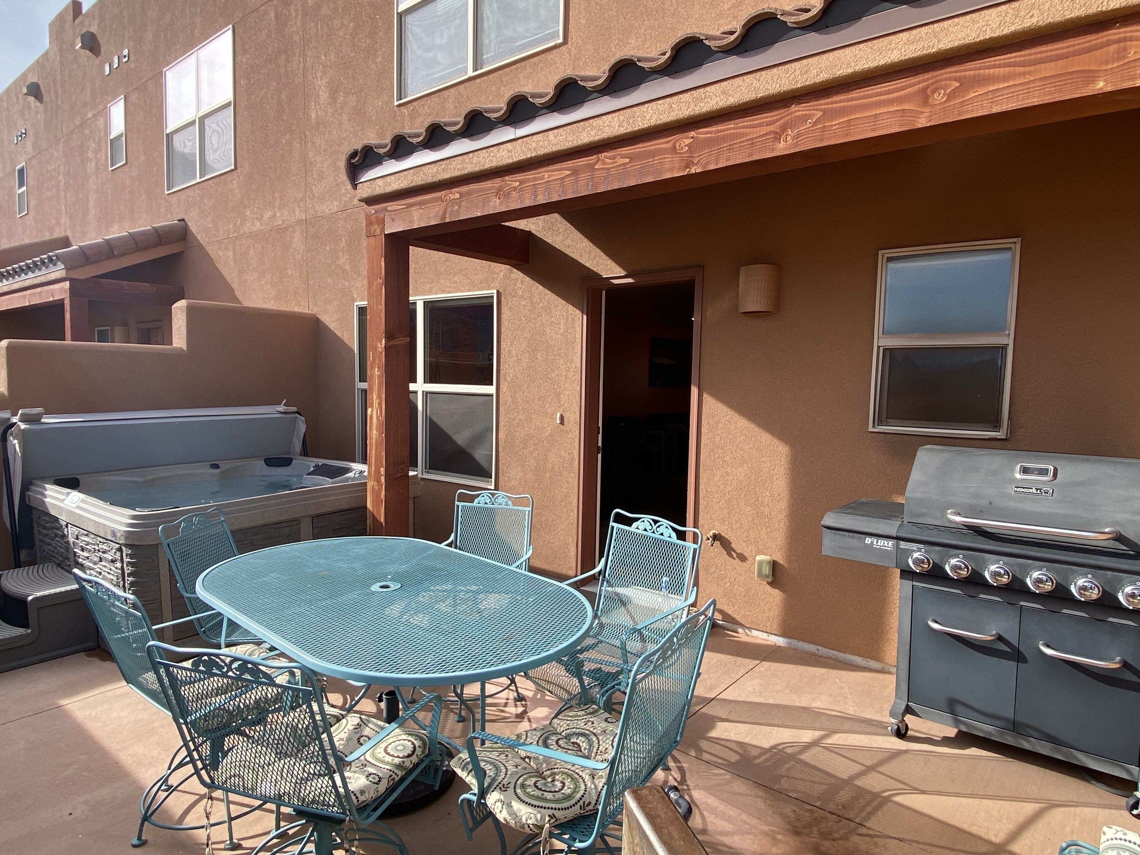 An outdoor patio with a round table and chairs, a hot tub, and a grill.