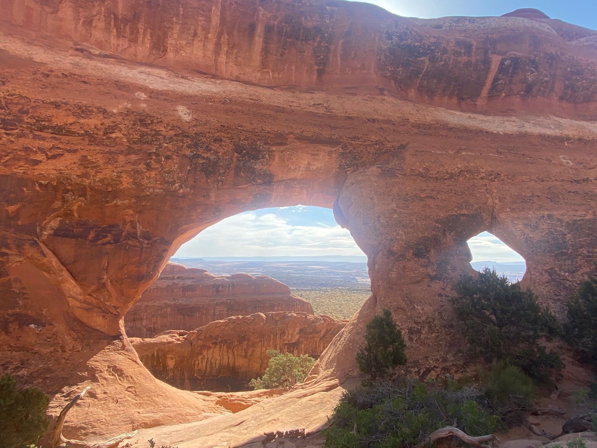 A natural rock arch formation with a view of the surrounding landscape.