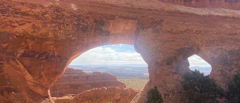 A natural rock arch formation with a view of the surrounding landscape.