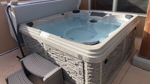 Un jacuzzi con revestimiento de piedra, una ventana y una silla.