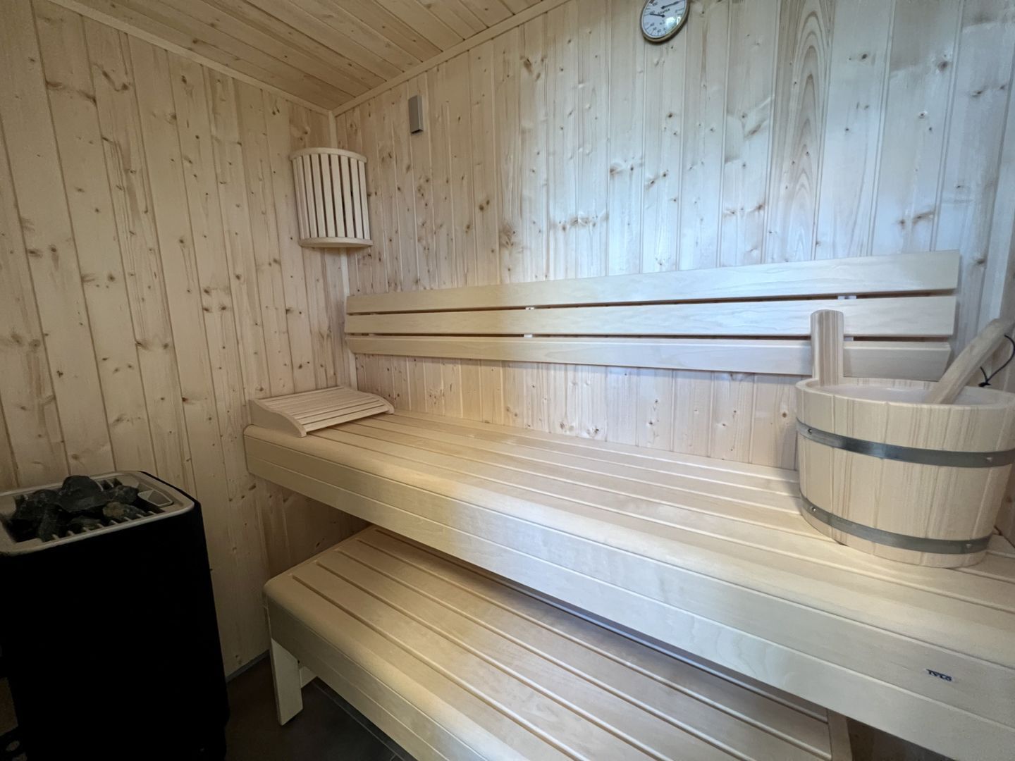 Un sauna avec des bancs en bois et un seau.