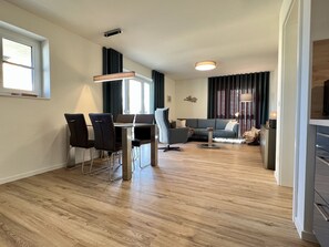 Ein modernes Wohnzimmer mit Essbereich, einer Couch und einem Fernseher.