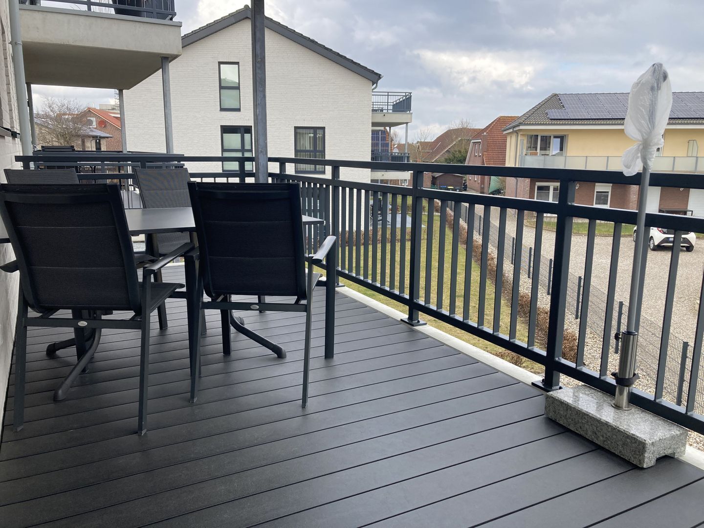 A balcony with a table and chairs, a railing, and a view of neighboring buildings.