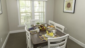 A dining room with a table set for four, including plates, cutlery, and a fruit bowl. - Spinnaker Resorts and
Cottages at King's Creek Resorts (Williamsburg)