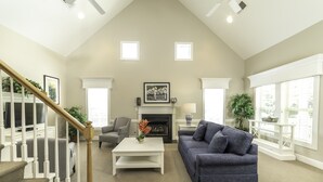 A spacious living room with a fireplace, a sofa, a coffee table, and a staircase. - Spinnaker Resorts and
Cottages at King's Creek Resorts (Williamsburg)