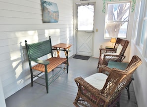 Relax in a charming outdoor space with a green metal chair, wicker seating, and a wooden table.