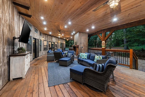 Une terrasse extérieure avec des meubles en osier, un téléviseur à écran plat et un plafond en bois.