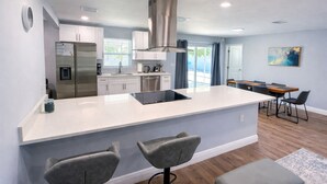 Una cocina moderna con una isla grande, electrodomésticos de acero inoxidable y un comedor con mesa y sillas.