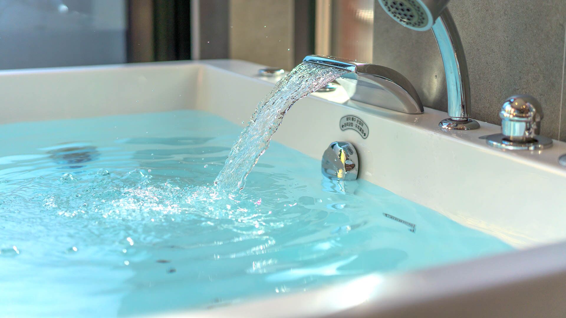 A bathtub with running water, a faucet, and a showerhead.