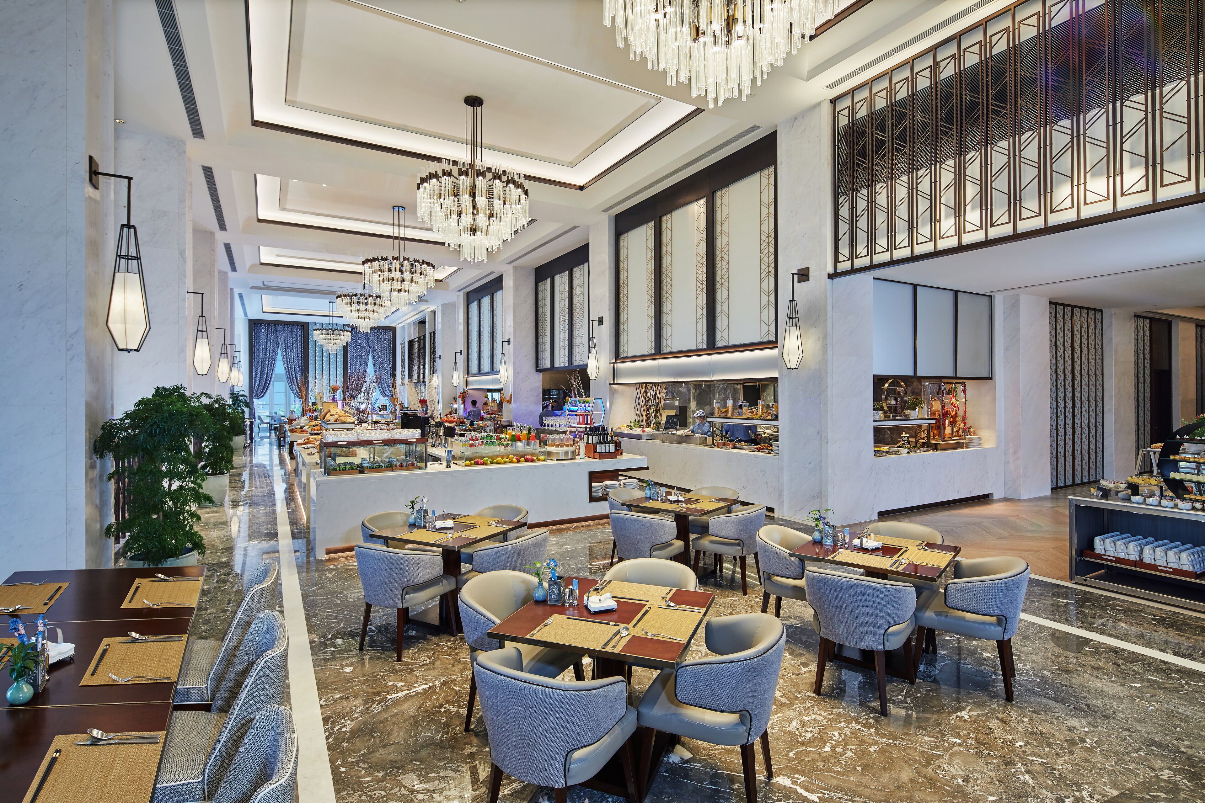 A modern hotel lobby with marble floors, multiple dining tables, and contemporary lighting fixtures.