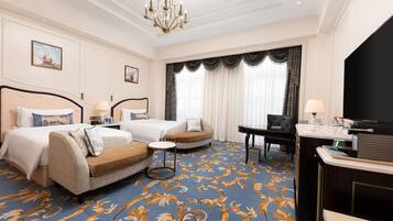 A hotel room with a large bed, two sofas, a desk, and a chandelier.