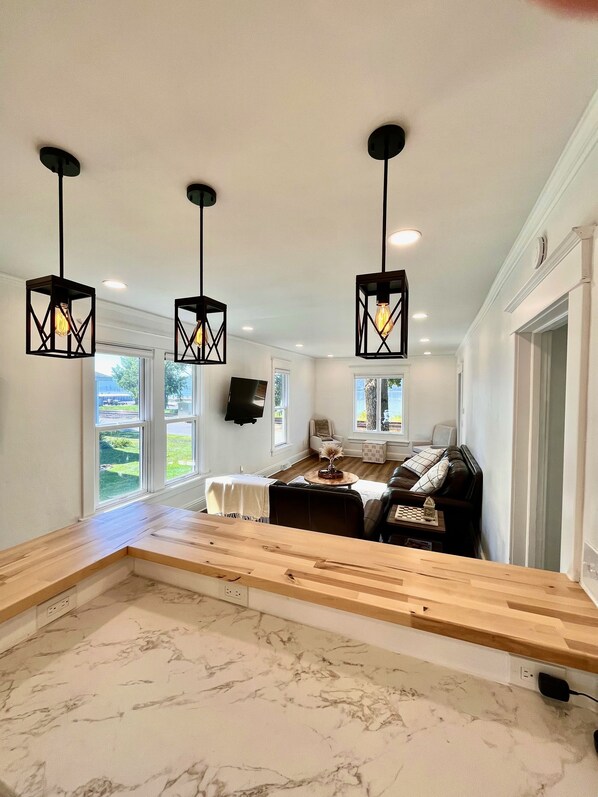 Uma cozinha moderna com bancadas de mármore, um banco de madeira e iluminação pendente.