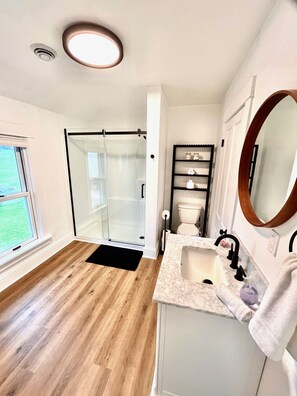 Une salle de bain moderne avec une douche en verre, un lavabo en marbre et un grand miroir.