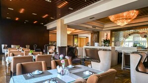 A hotel lobby with dining tables set for guests, a bar area, and a chandelier. - Hebei Cuipingshan Guest House (Shijiazhuang)