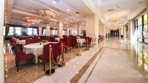 A spacious dining area with round tables and red chairs, a marble floor, and a chandelier. - Hebei Cuipingshan Guest House (Shijiazhuang)