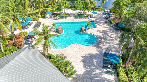 Ein Resort mit großem Pool, umgeben von Palmen und Liegestühlen.