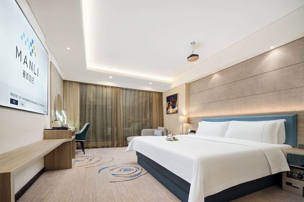 Ein modernes Hotelzimmer mit einem großen Bett, einem Schreibtisch und einem Stuhl.