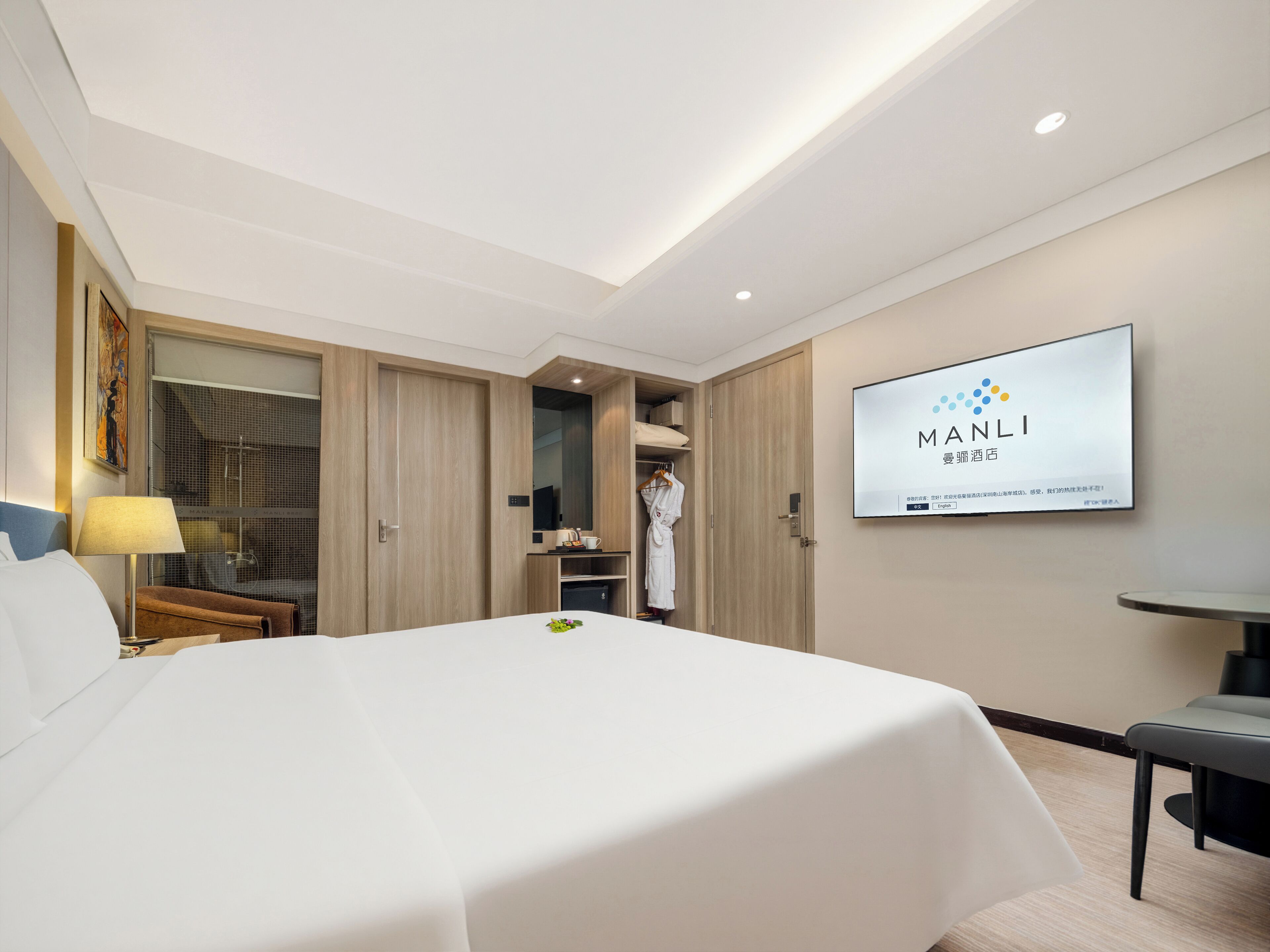A modern hotel room with a large bed, a TV mounted on the wall, and a walk-in closet.