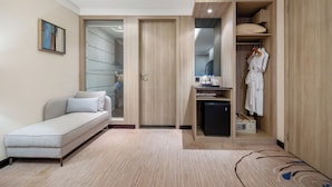 Ein modernes Hotelzimmer mit einer Couch, einer kompakten Küchenzeile, einem begehbaren Kleiderschrank und einem Oberlicht.