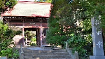 A traditional Japanese gate with stone steps leading up to it, surrounded by lush greenery.