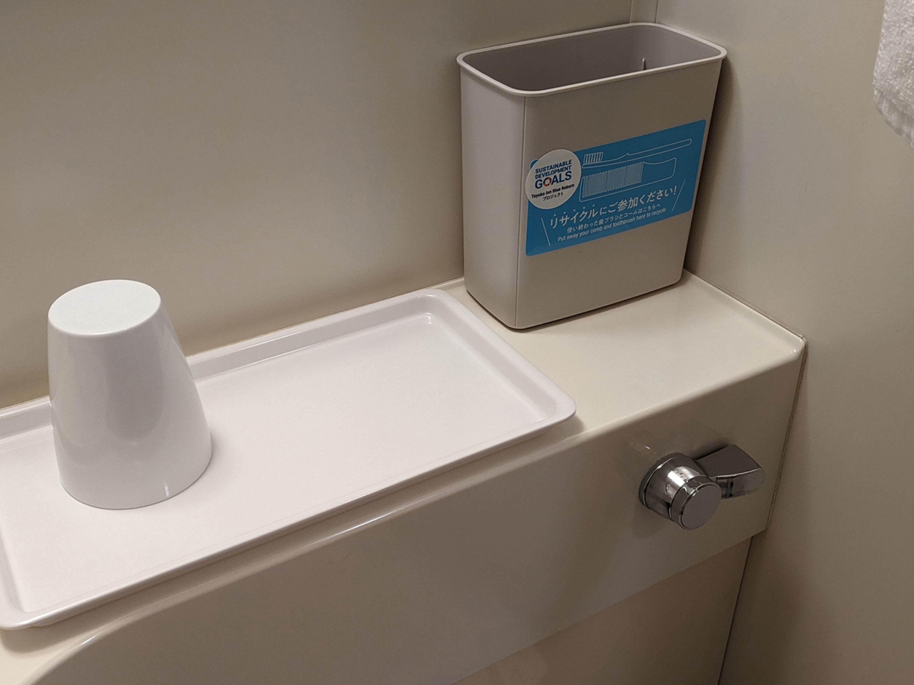 Un inodoro con un orinal blanco, un cesto de basura y un contenedor para reciclaje.