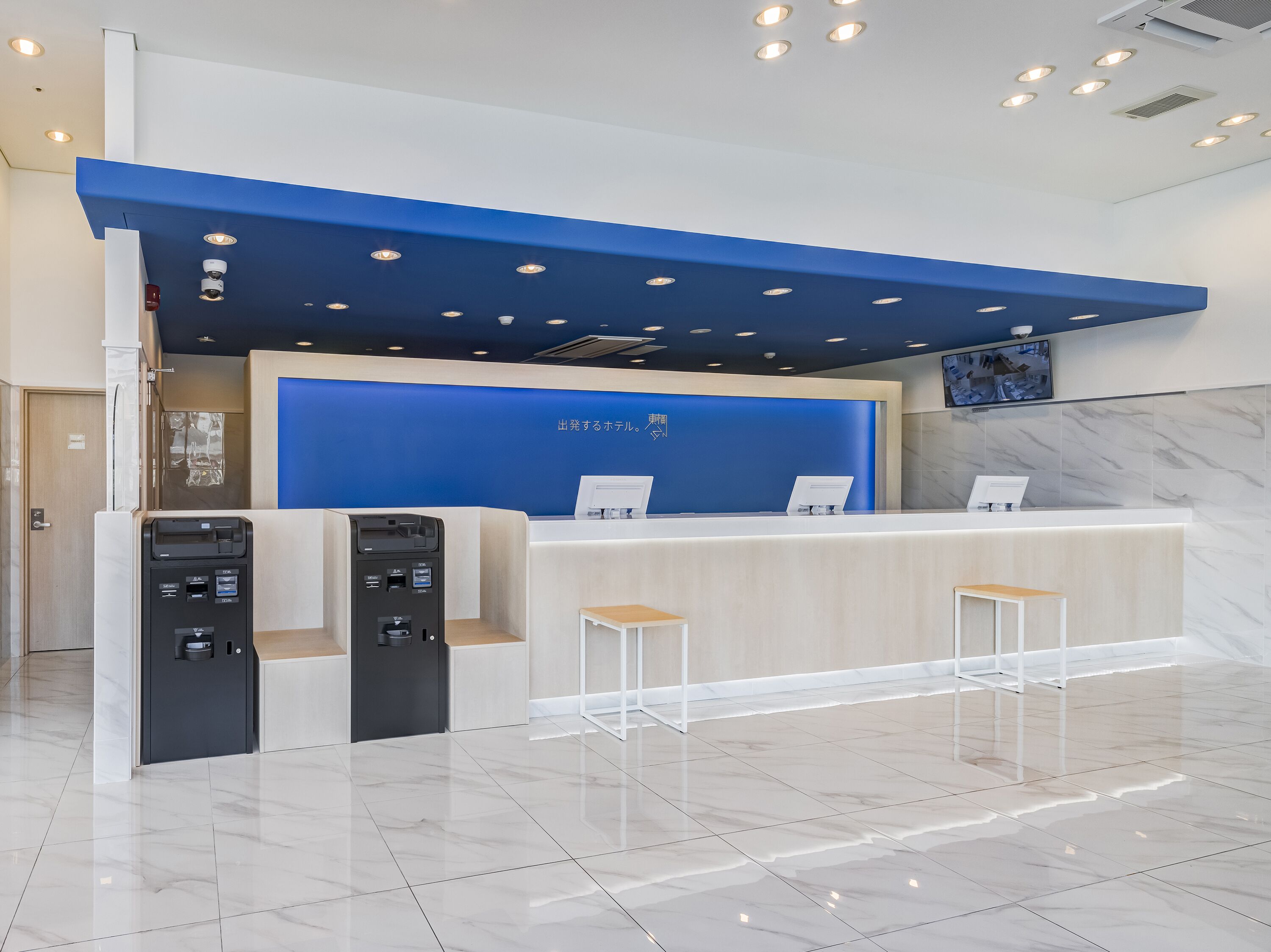 Un comptoir d’accueil moderne, agrémenté d’un mur d’accent bleu, d’un téléviseur à écran plat placé au-dessus et d’un sol en marbre.