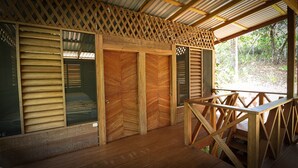 Una cabaña de madera con un porche cubierto, puertas correderas grandes y vistas del bosque circundante.
