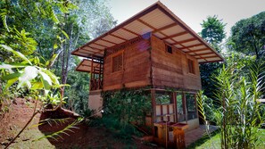 A wooden structure with a sloped roof and a balcony, surrounded by dense greenery. - Finca el encanto sierpe (Sierpe de osa)