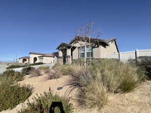 A residential house with a stone facade, multiple windows, and a clear blue sky. - Former Model Home, 3 Car Garage, Gym, Sleep 14 (Lancaster)