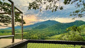 Un edificio moderno con fachada de vidrio que ofrece vistas a un paisaje verde exuberante y montañas distantes.
