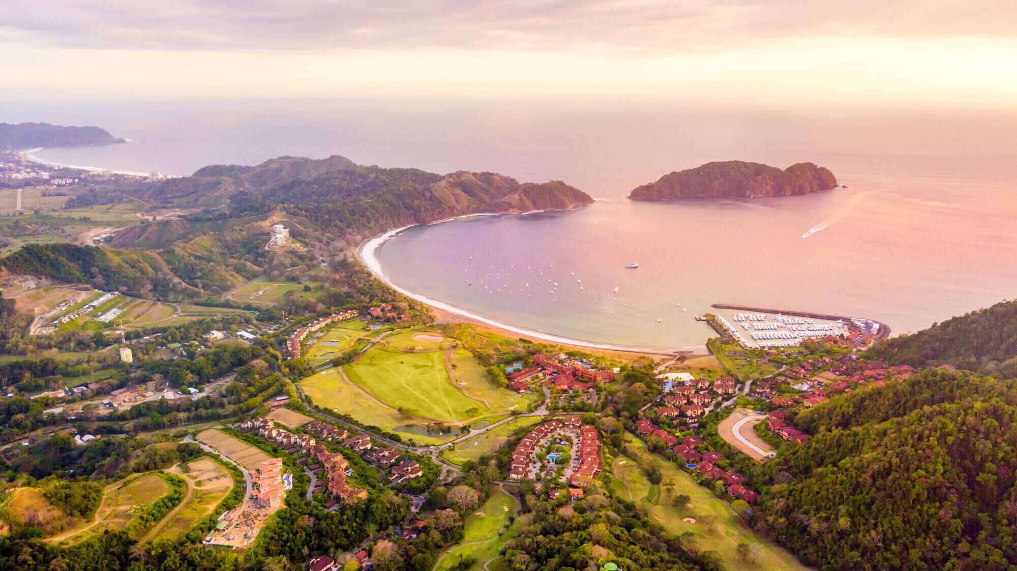 Vista aérea de una zona costera con playa, edificios residenciales y un campo de golf.