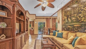 Un salon spacieux avec un grand canapé, des meubles en bois et un ventilateur de plafond.