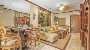 Un salon spacieux comprenant un coin repas, un ensemble de canapés et un ventilateur de plafond.