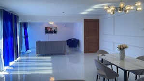 Ein modernes Wohnzimmer mit Essbereich, einem an der Wand montierten Fernseher und einer Holztür.