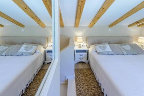 Two beds with matching nightstands and lamps, surrounded by a textured rug and a mirror.