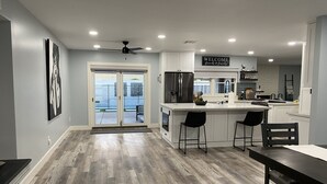 A modern kitchen with a central island, bar stools, and a dining table.