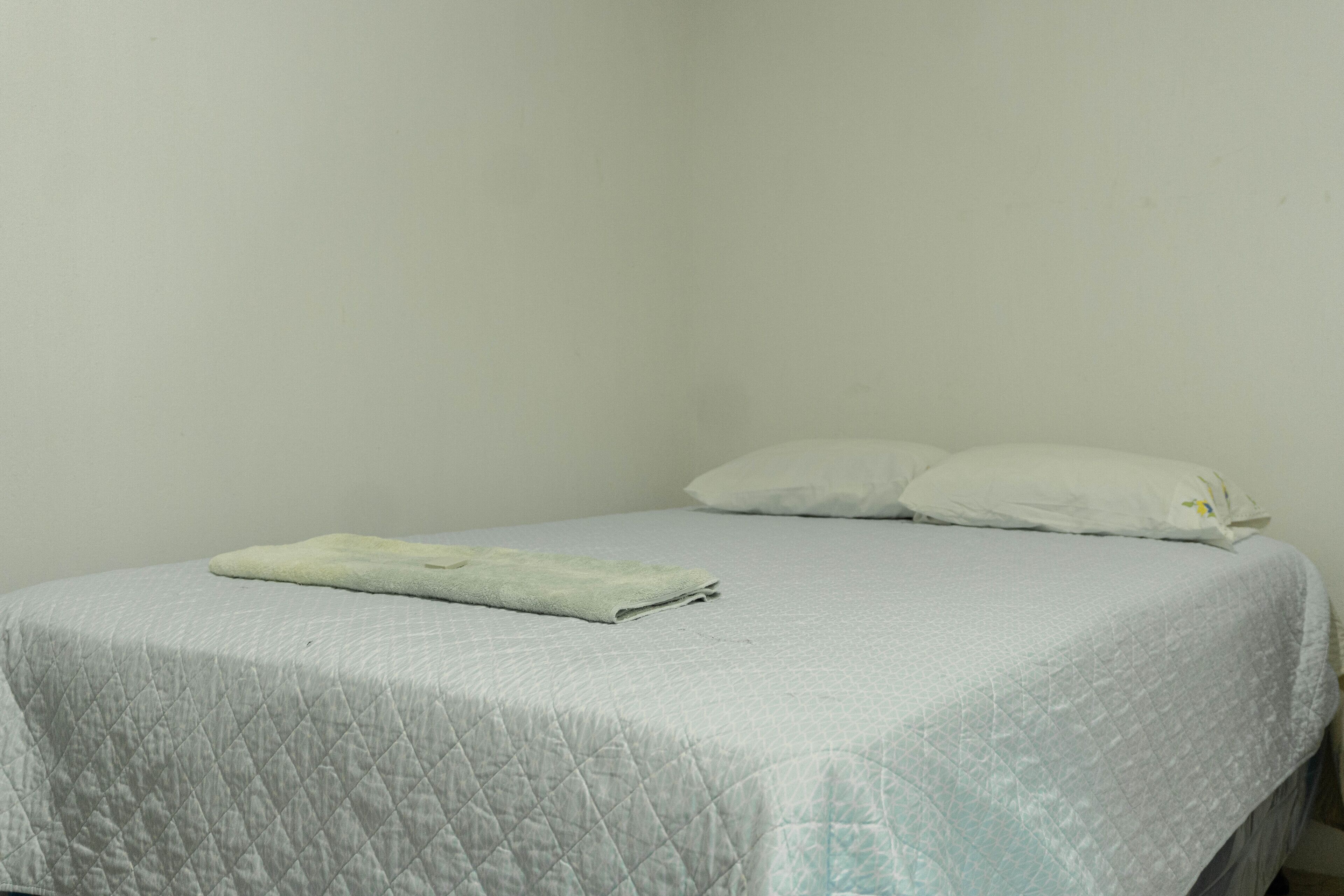 Uma cama de solteiro com colcha acolchoada e duas almofadas.