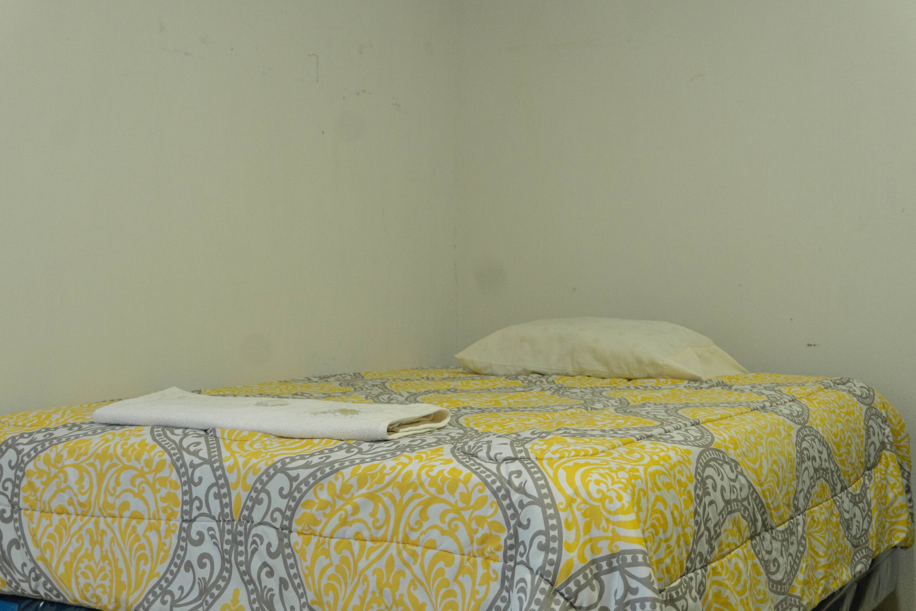 A bed with a patterned bedspread and a folded white towel.