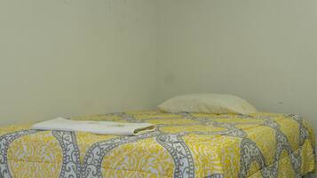 A bed with a patterned bedspread and a folded white towel.