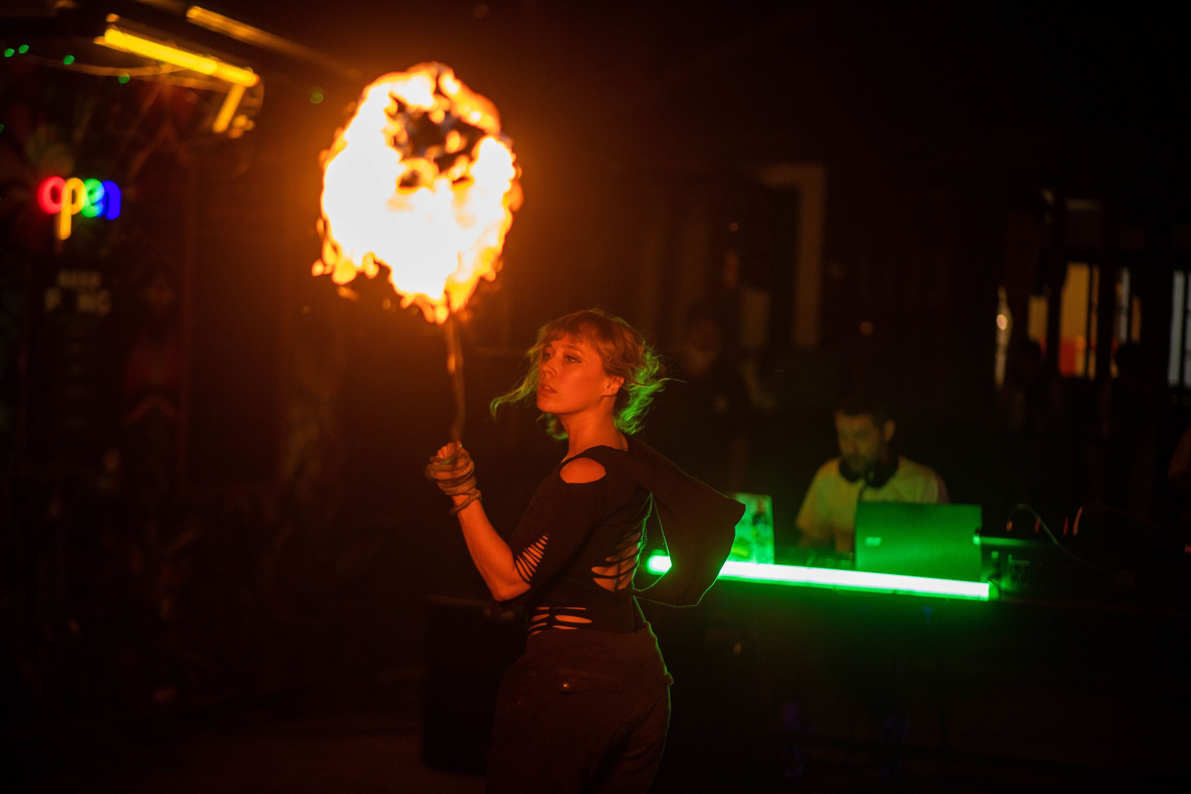 A person performing with a flaming object in a dimly lit indoor setting.