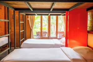 Una habitación con dos camas, paredes de madera y vista a zonas verdes.