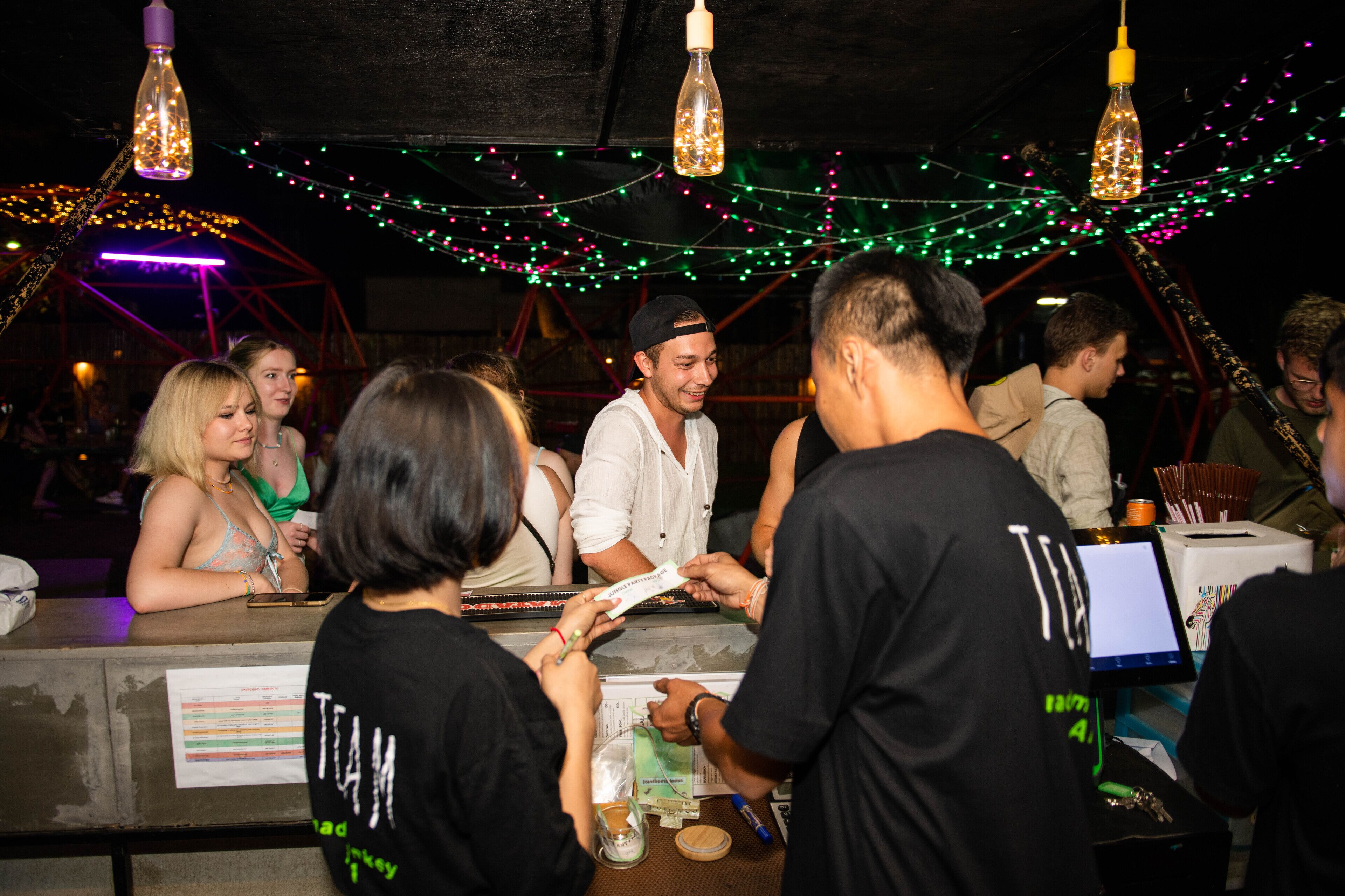 A bar area with a counter, hanging light fixtures, and festive string lights.